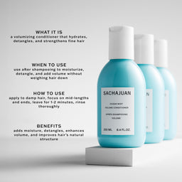 A bottle of Sachajuan Ocean Mist Volume Conditioner stands on a white pedestal against a light gray background, with two more bottles behind it. Text on the image describes the conditioner's function, usage, and benefits.