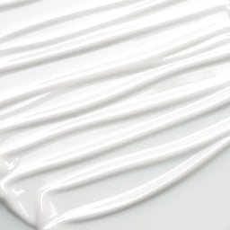A close-up of thick, glossy white cream or paint swirled in diagonal streaks on a white surface.