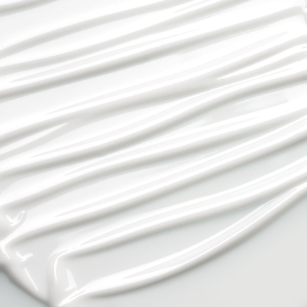 A close-up of thick, glossy white cream or paint swirled in diagonal streaks on a white surface.