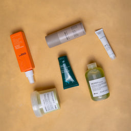 Collection of skincare products on a beige surface