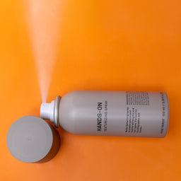 Spray can labeled 'HANDS-ON' on an orange background