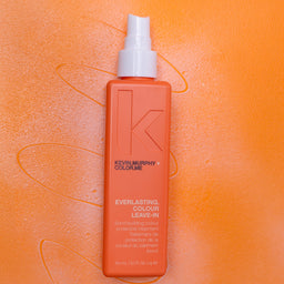 Orange bottle of Kevin Murphy hair product on an orange background