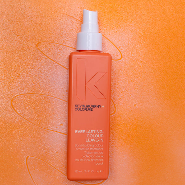 Orange bottle of Kevin Murphy hair product on an orange background