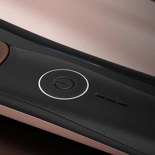 Close-up of a sleek hair straightener showing its matte black control panel with a glowing power button and rose gold metallic accents.