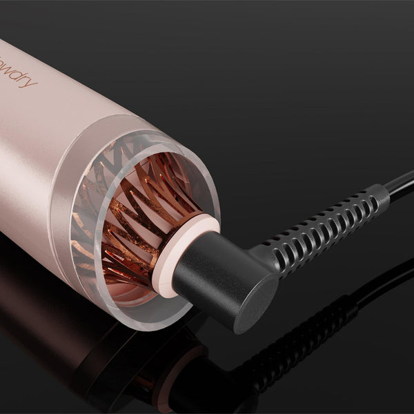 A close-up of a hair styling tool with a metallic rose gold body, showing the copper heating plates inside the barrel and a black cord plugged in on a glossy black background.