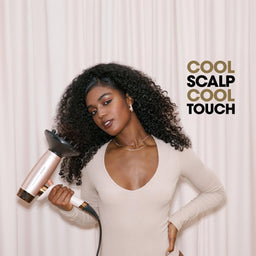 A woman with voluminous curly hair holds a rose gold and black hair dryer with a concentrator nozzle against her hair, posing in front of a cream-colored curtain. The text 'COOL SCALP COOL TOUCH' is displayed on the right side.
