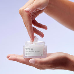 Person applying KERASTILK cream to their hand against a light purple background