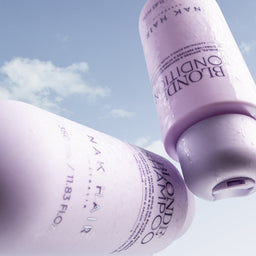 Two bottles of Nak Hair Shampoo and Conditioner against a blue sky background