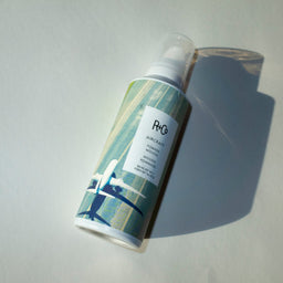 a closeup  of a R+Co Aircraft Pomade Mousse bottle