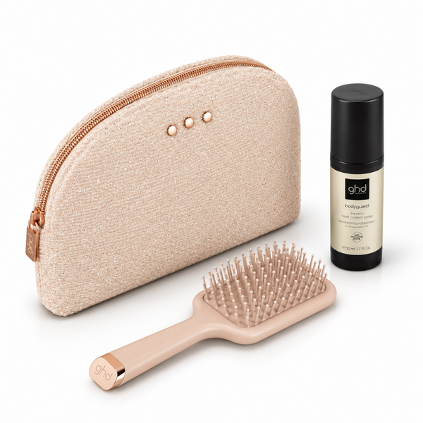 Ghd haircare travel set featuring a rose gold zippered case, a peach-colored paddle brush, and a black-and-gold bottle of Ghd Contour Spray on a white background.