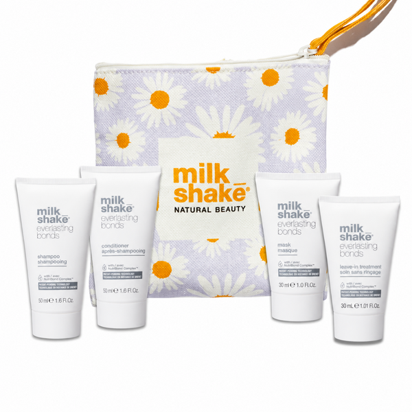 Milk Shake Everlasting Bonds hair care set with a lavender and white daisy-patterned zip pouch and four white bottles of shampoo, conditioner, mask, and treatment on a white background.