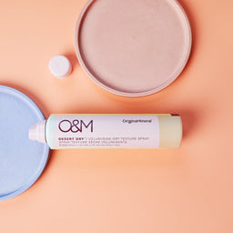 O&M Desert Dry Texture Spray bottle on a salmon pink surface