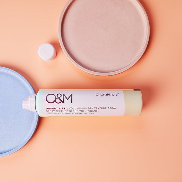O&M Desert Dry Texture Spray bottle on a salmon pink surface