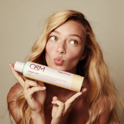 a model holding O&M Desert Dry Texture Spray close to her face